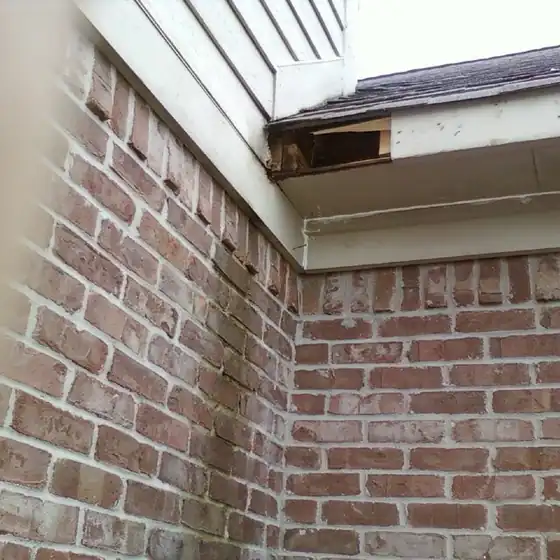 Brick corner under a roof edge where a section of the soffit and fascia board is open and exposed