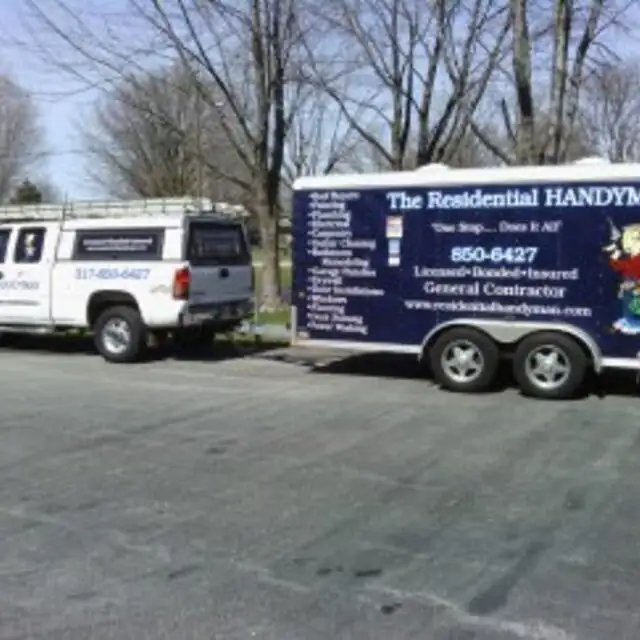 White pickup truck towing a navy enclosed trailer lettered The Residential Handyman, parked on a street