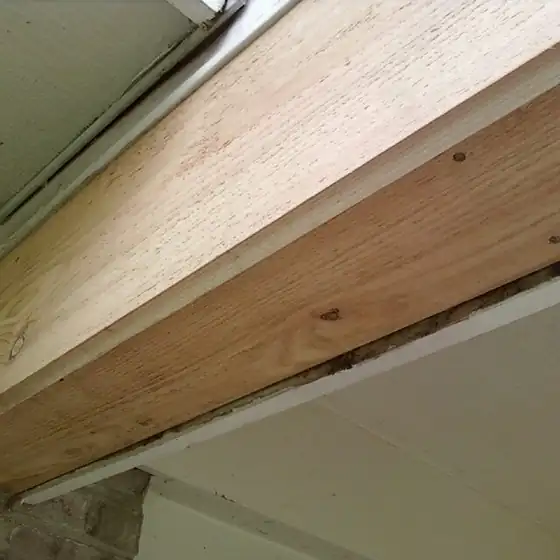 New unpainted wood fascia board fitted tight under the roof edge, seen from below