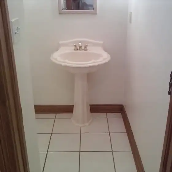 Finished half bath with a pedestal sink, white tile floor and painted walls