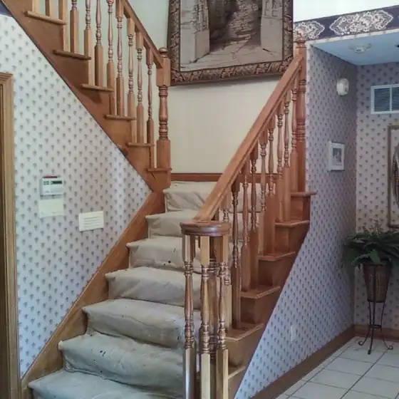 Staircase with protective paper on the treads and masked railing before painting