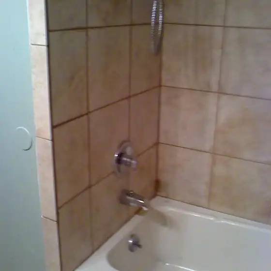 Beige ceramic tile tub surround with a chrome faucet and diverter